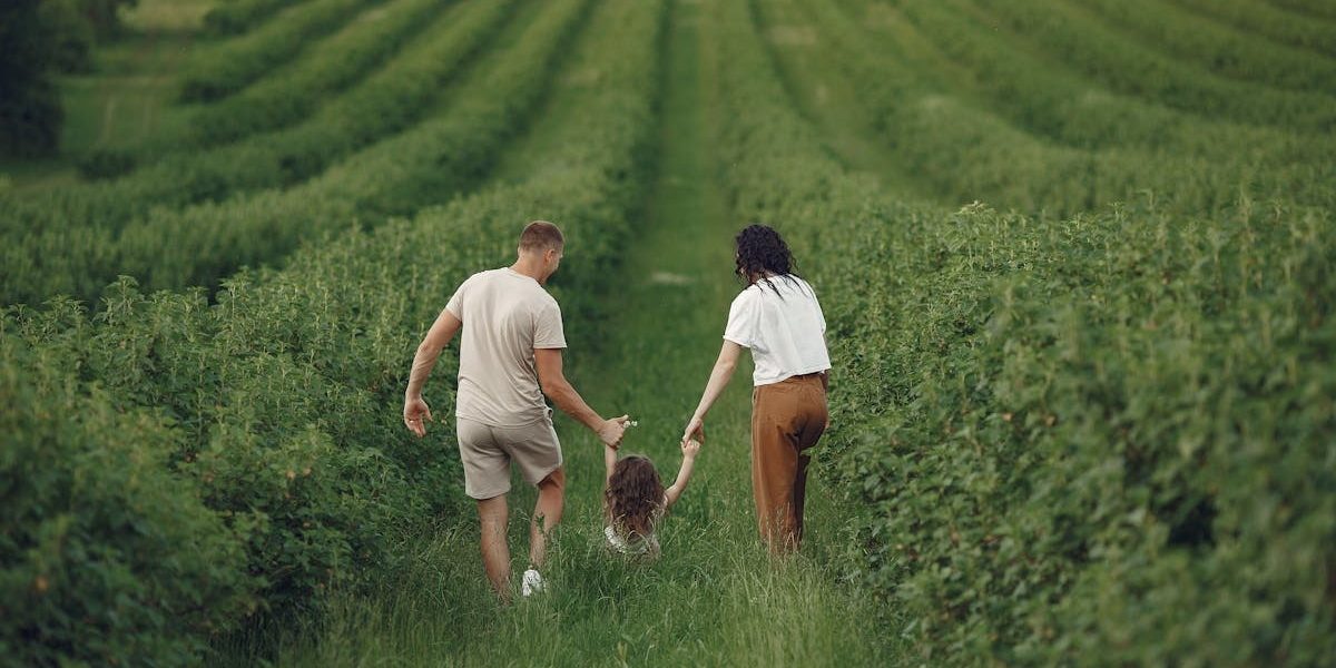 Happy family walking together through a lush green field enjoying nature and togetherness.
