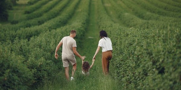 Happy family walking together through a lush green field enjoying nature and togetherness.